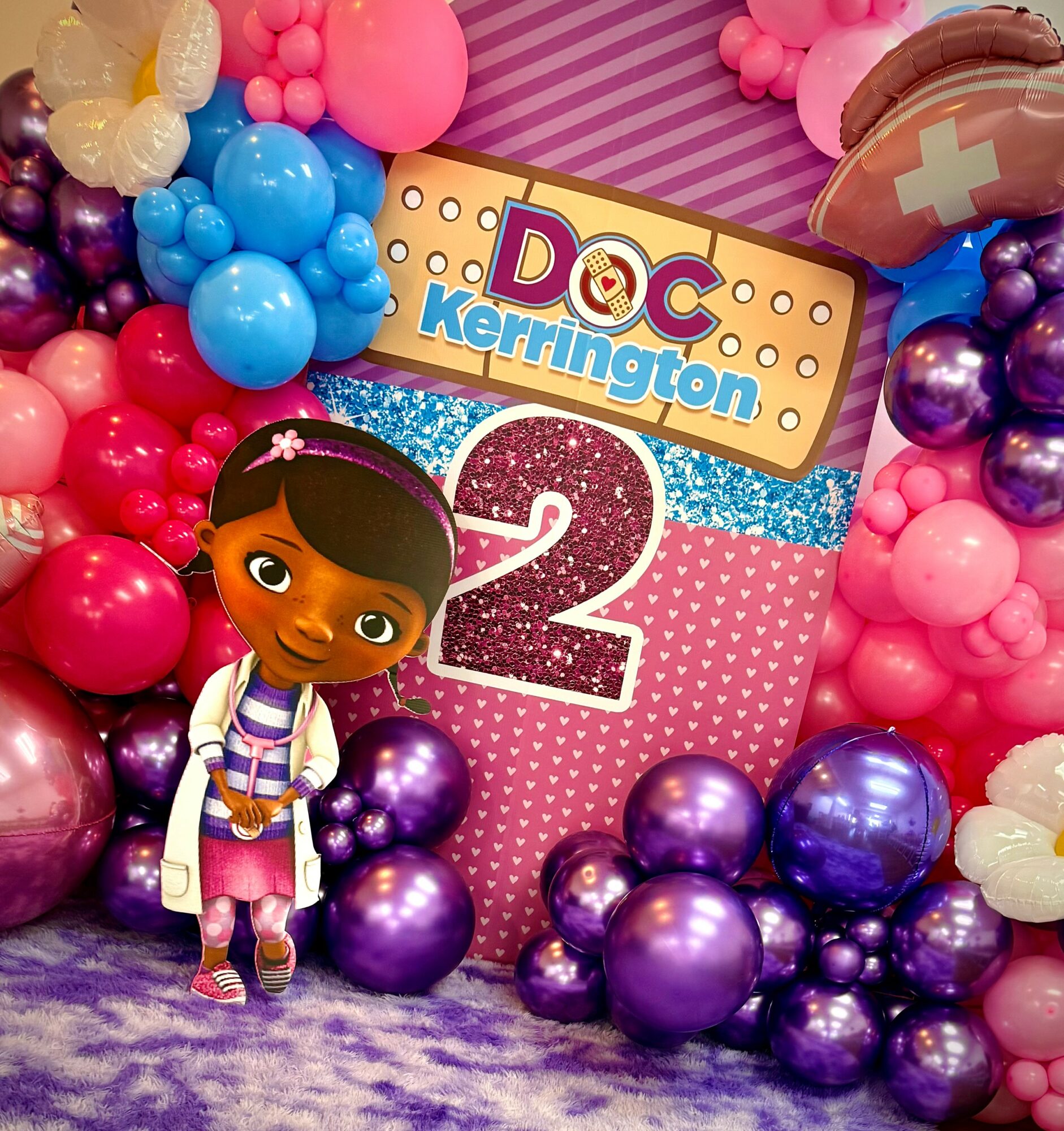 Decorative birthday display with balloons, a cartoon girl, and a sign reading 'DOC Kerrington 2'.