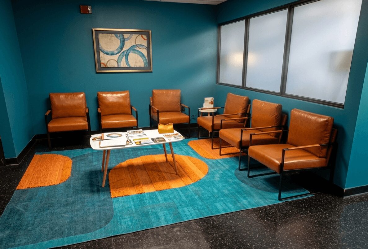 Waiting room with six brown chairs, a white table, and a window with frosted glass.