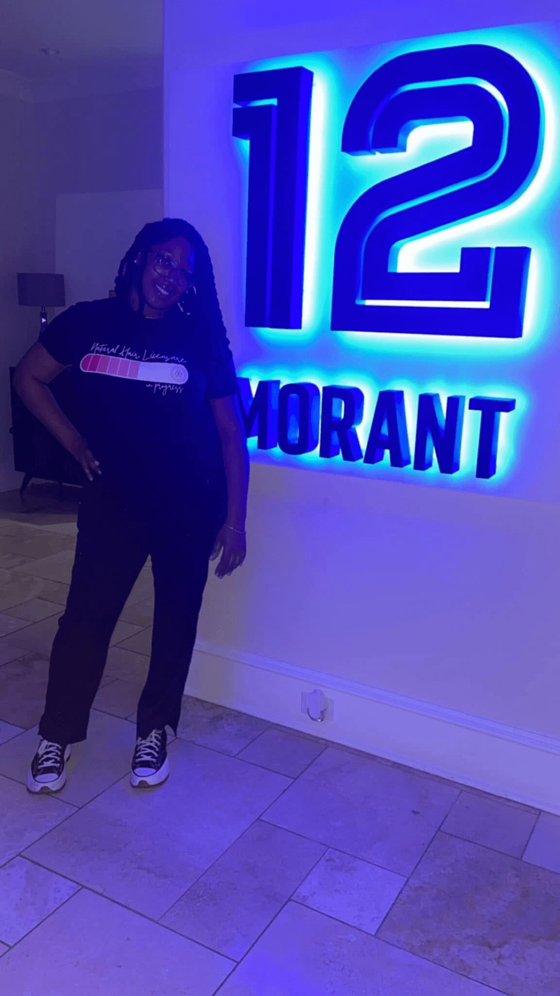 Person standing indoors near illuminated sign with large number 12 and the word MORANT.