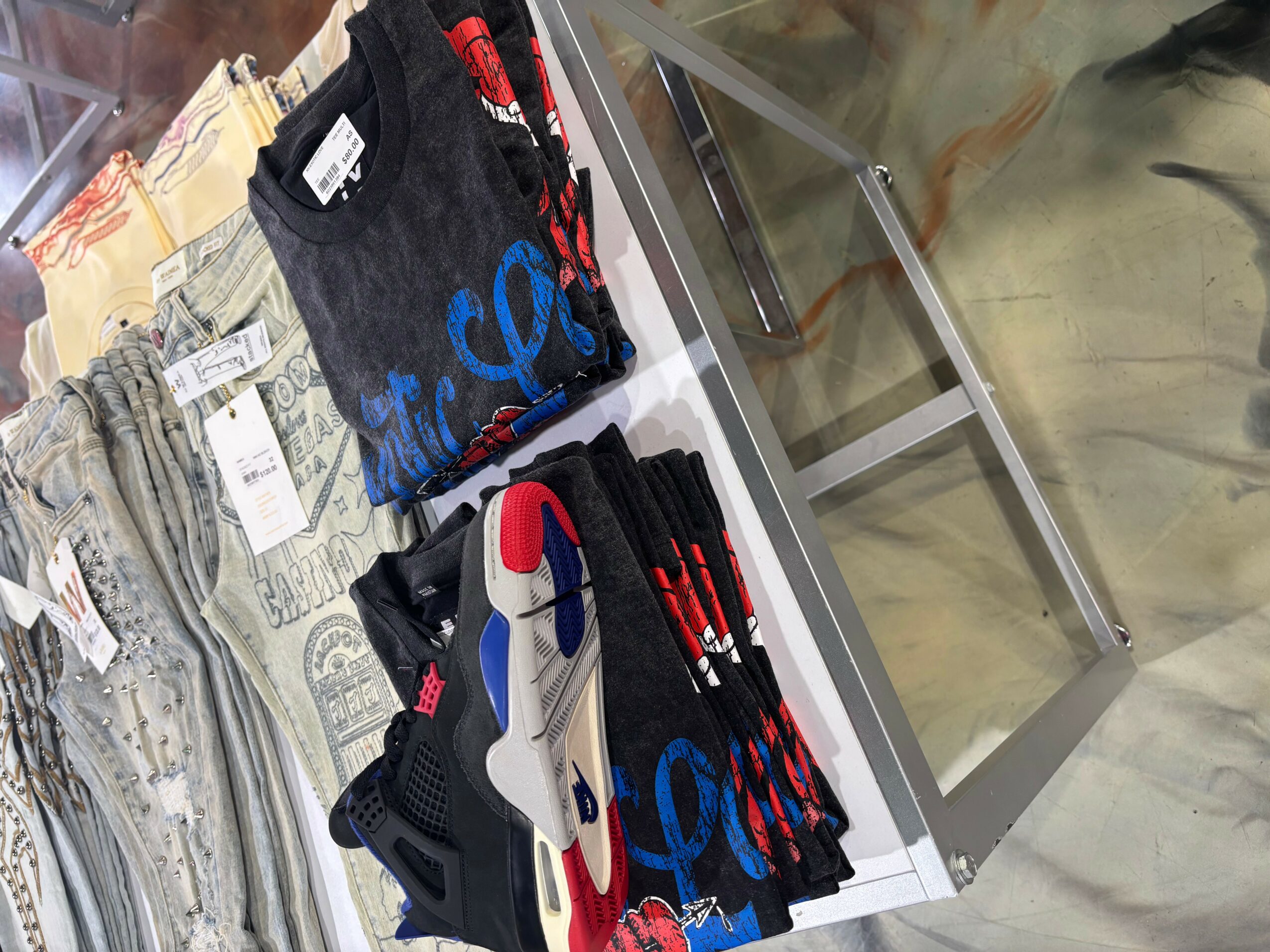 Display of folded clothing and socks on a glass table, with a person in the background. The image is rotated 90 degrees clockwise.