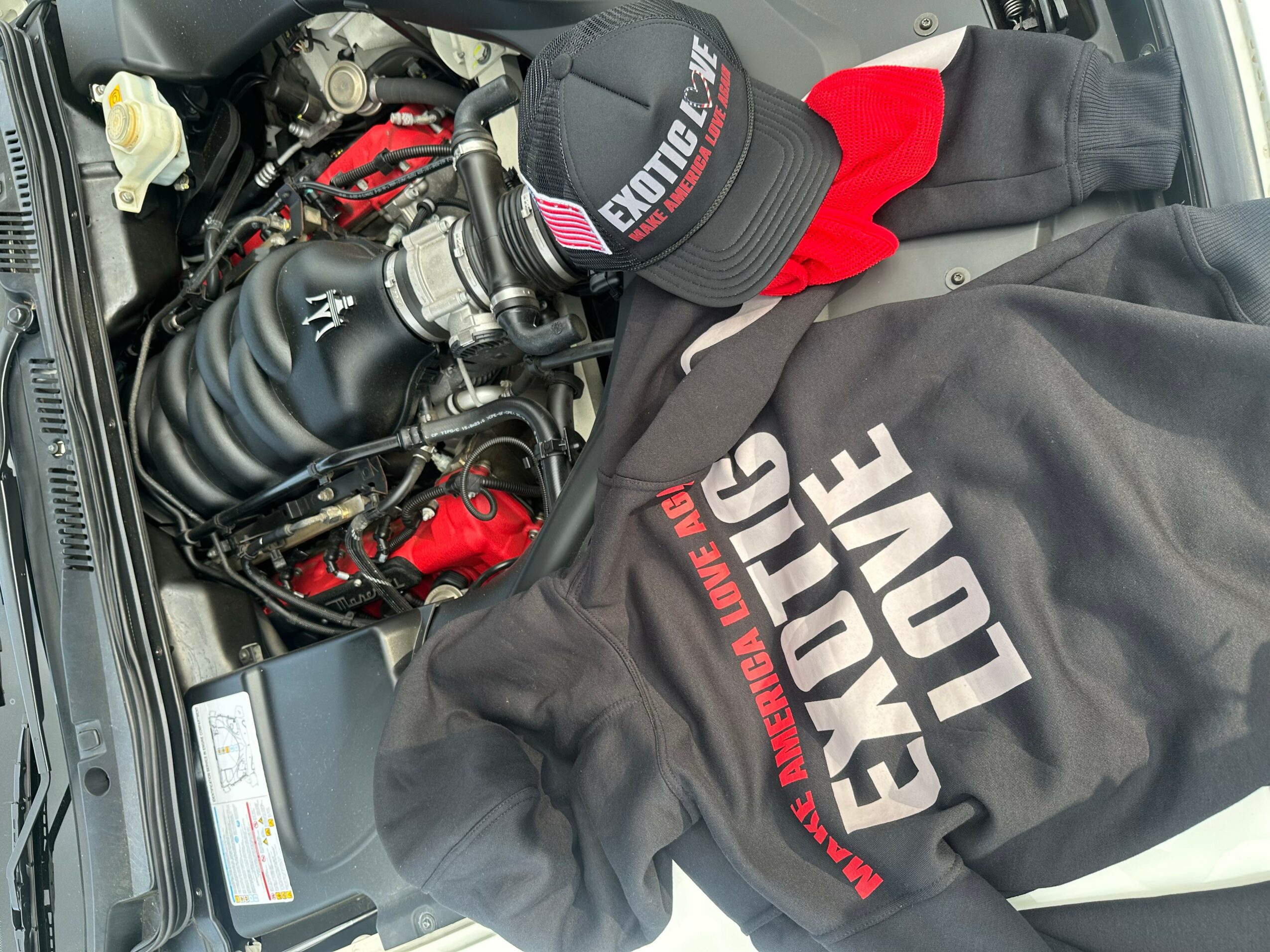 Car engine with a cap and clothing placed on top, engine components visible, including hoses and wiring.