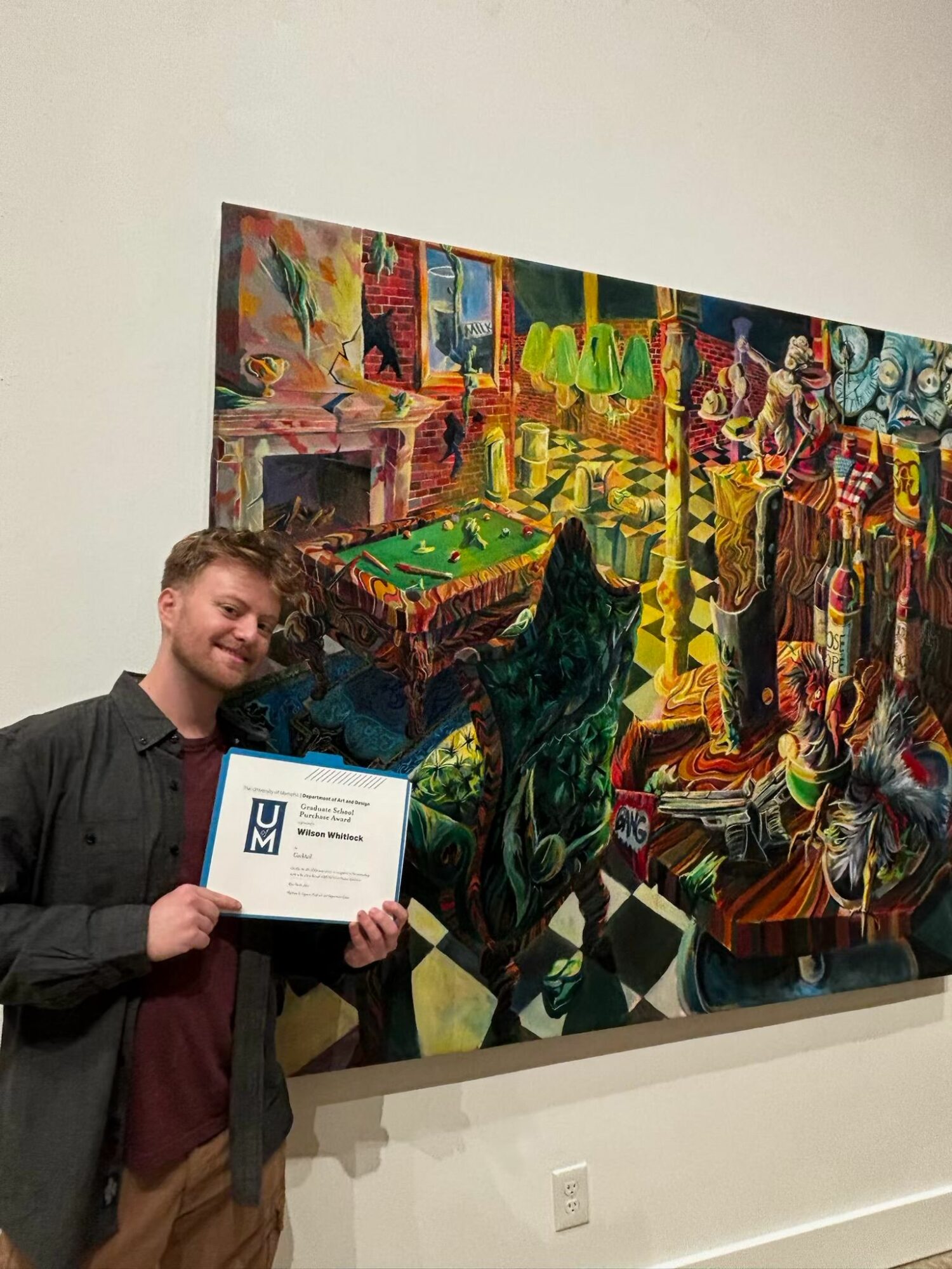 Person holding a certificate in front of a colorful abstract mural, standing indoors. The person has curly hair and is wearing a dark jacket.