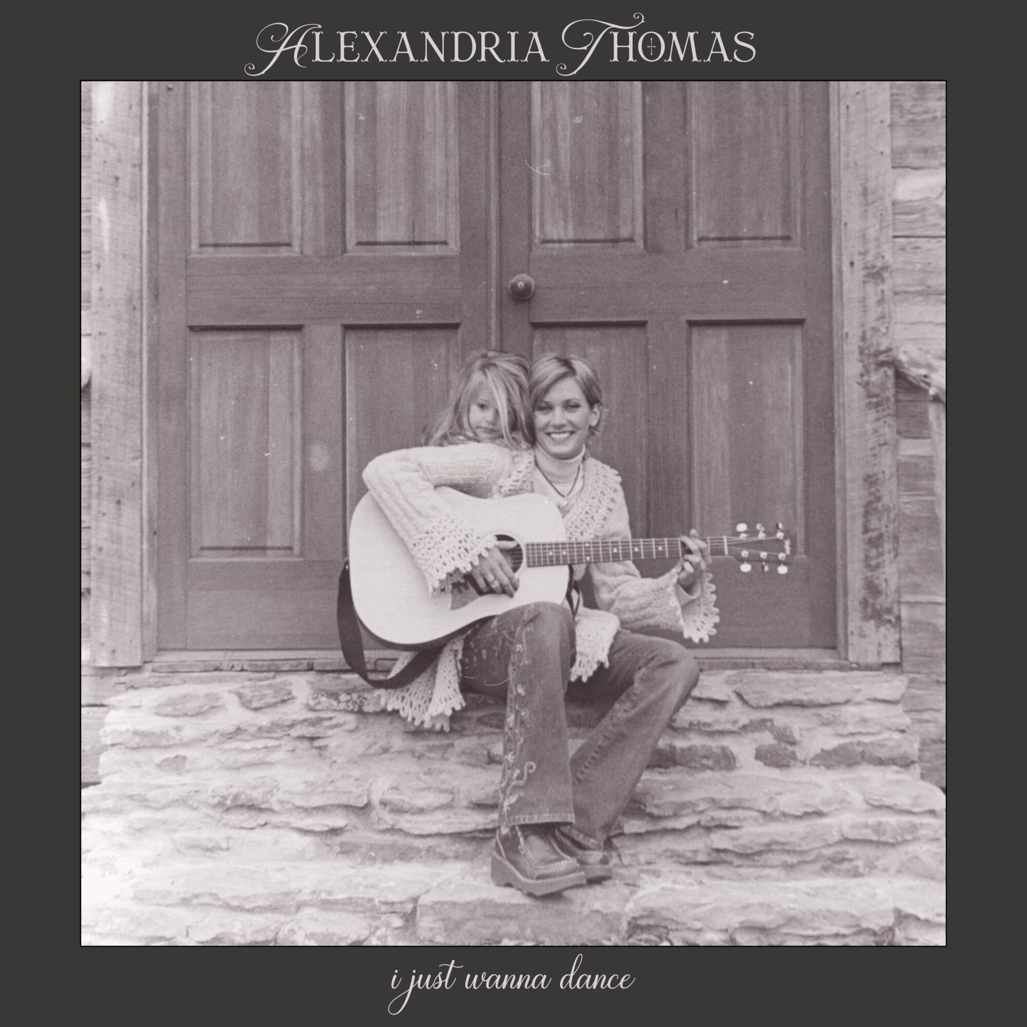 Two women sit on stone steps in front of a wooden door, one playing guitar, smiling. Album title and artist at top.