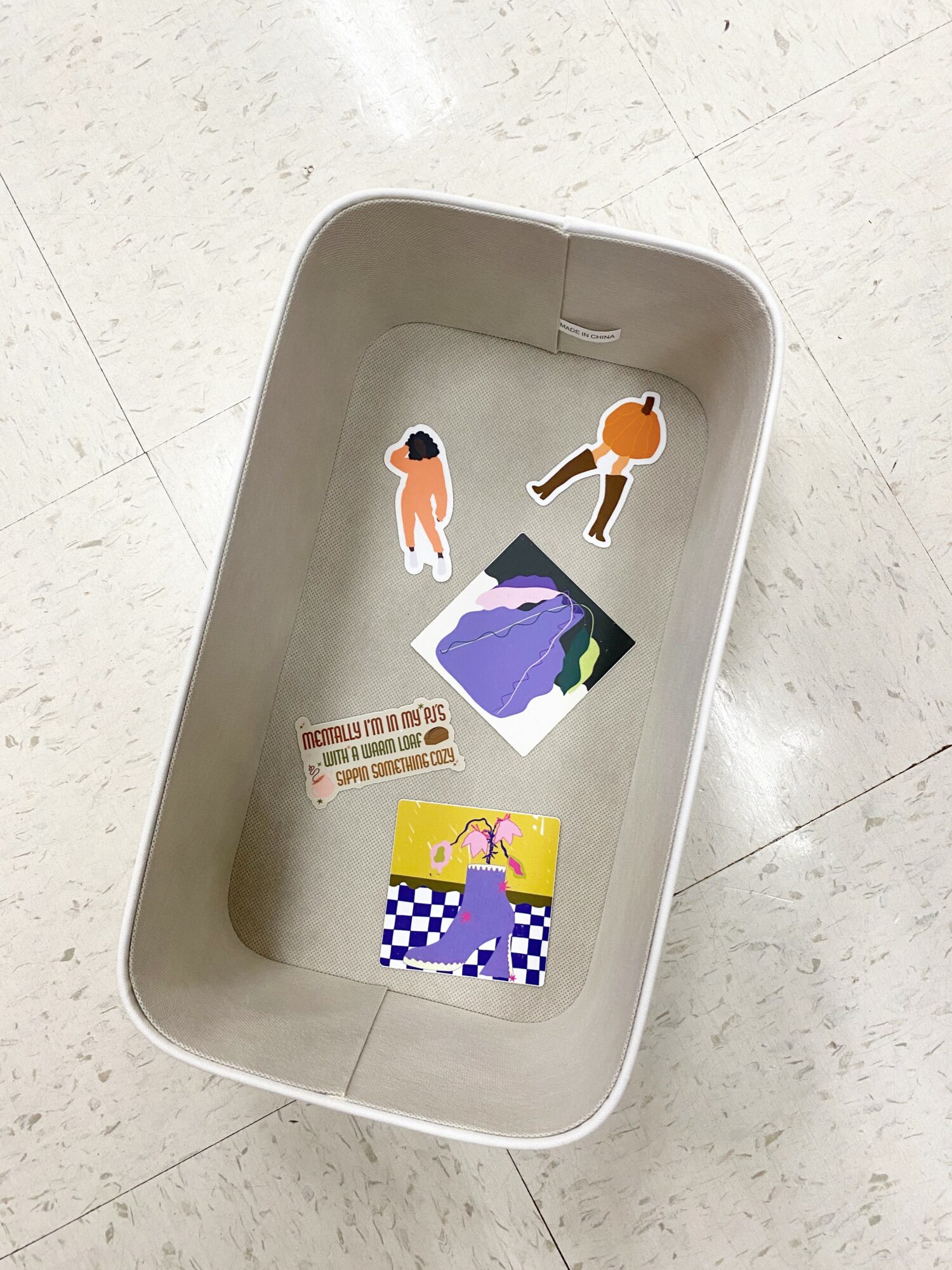 Empty white tray with stickers inside, on a tiled floor.