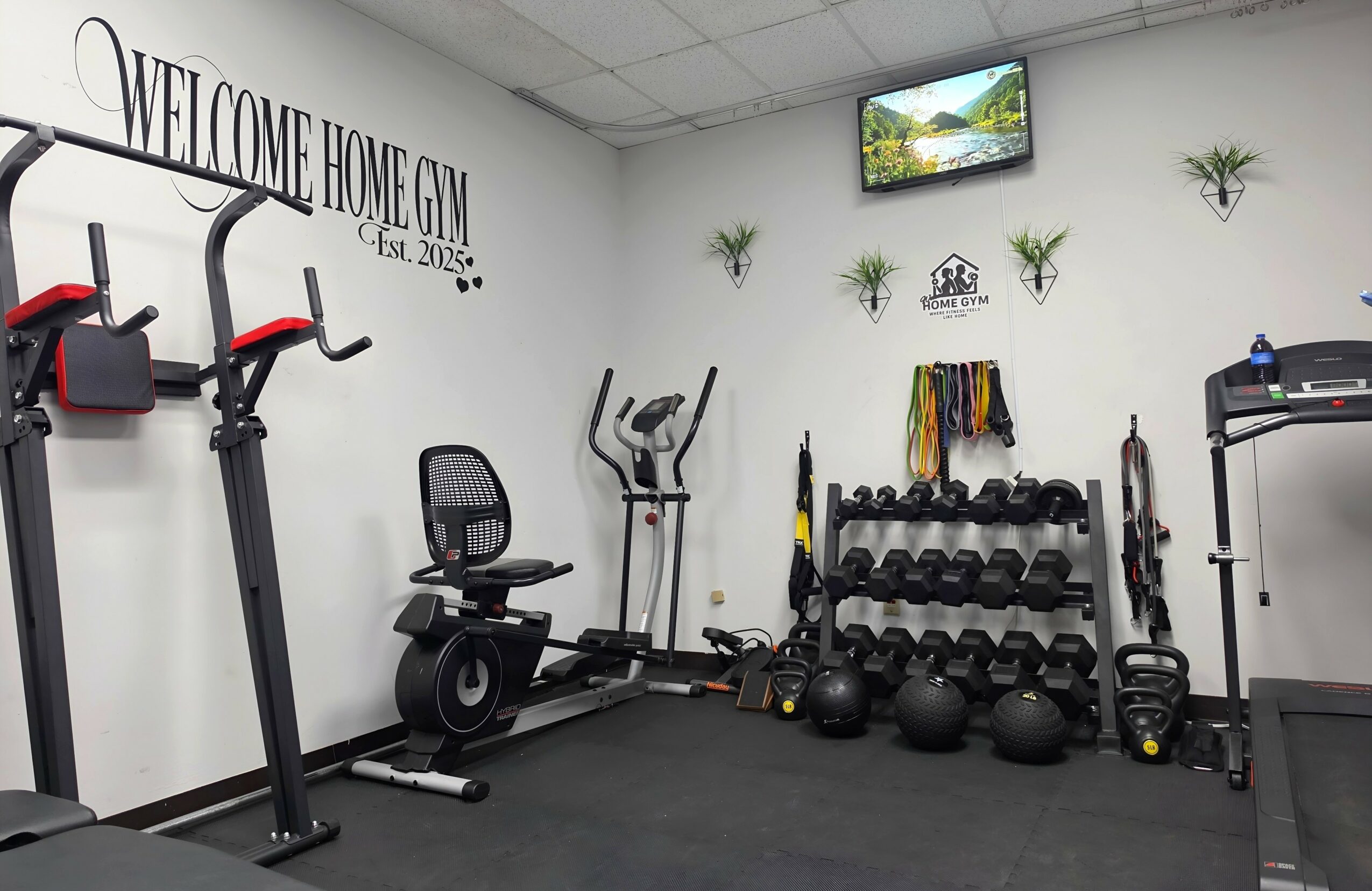 Gym room with exercise equipment, wall decor, and a TV mounted on the wall.