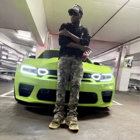Person standing in front of a bright green sports car in an underground parking garage.