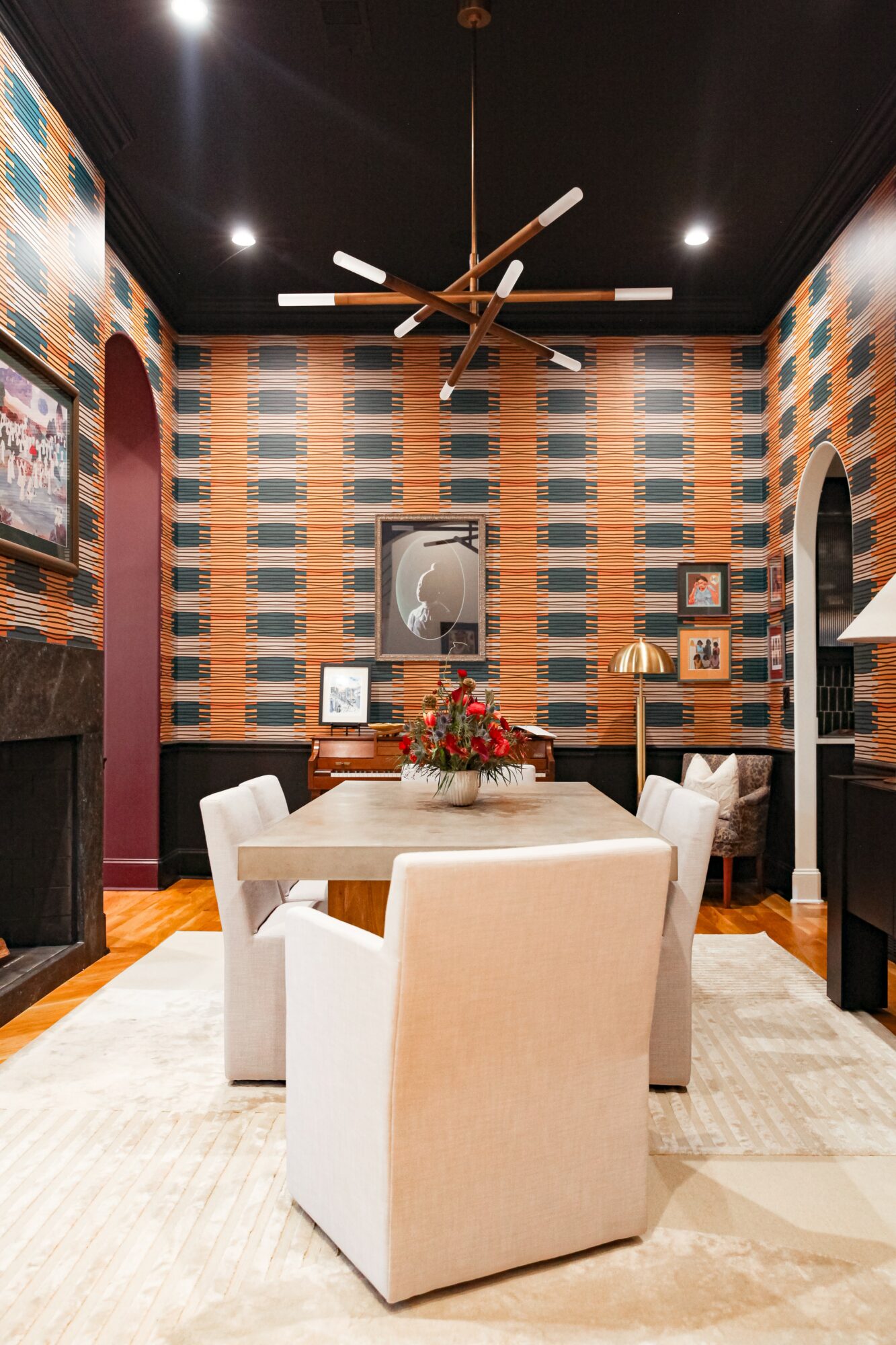 Dining room with patterned wallpaper, a wooden table with a floral centerpiece, six white chairs, and a ceiling fan.