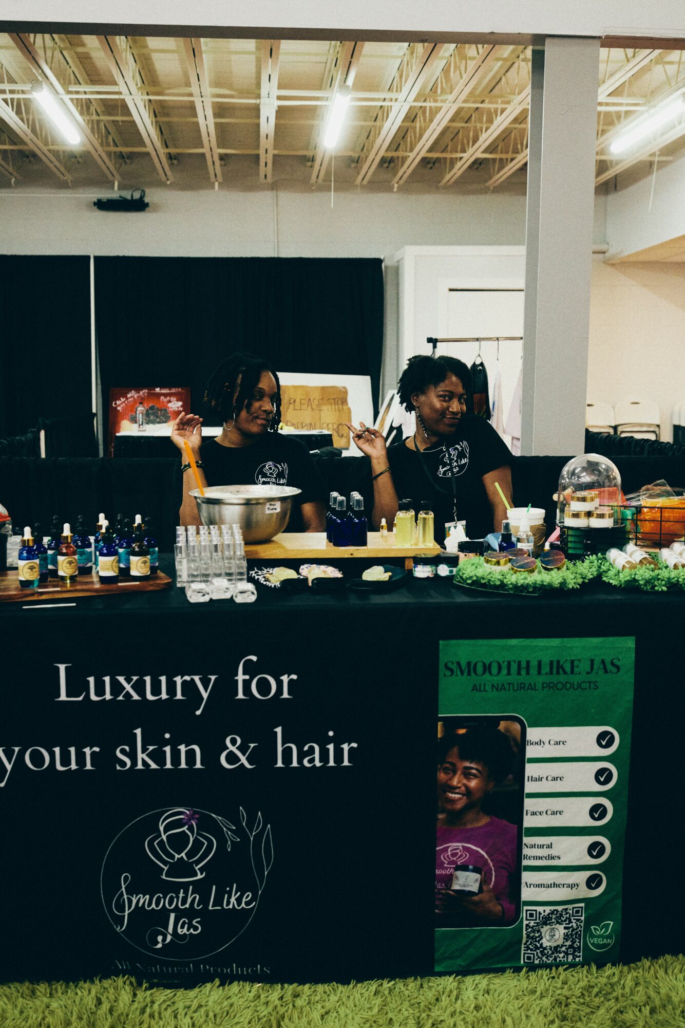 Three women behind a hair product display counter in a store, with shelves and products visible in the background.