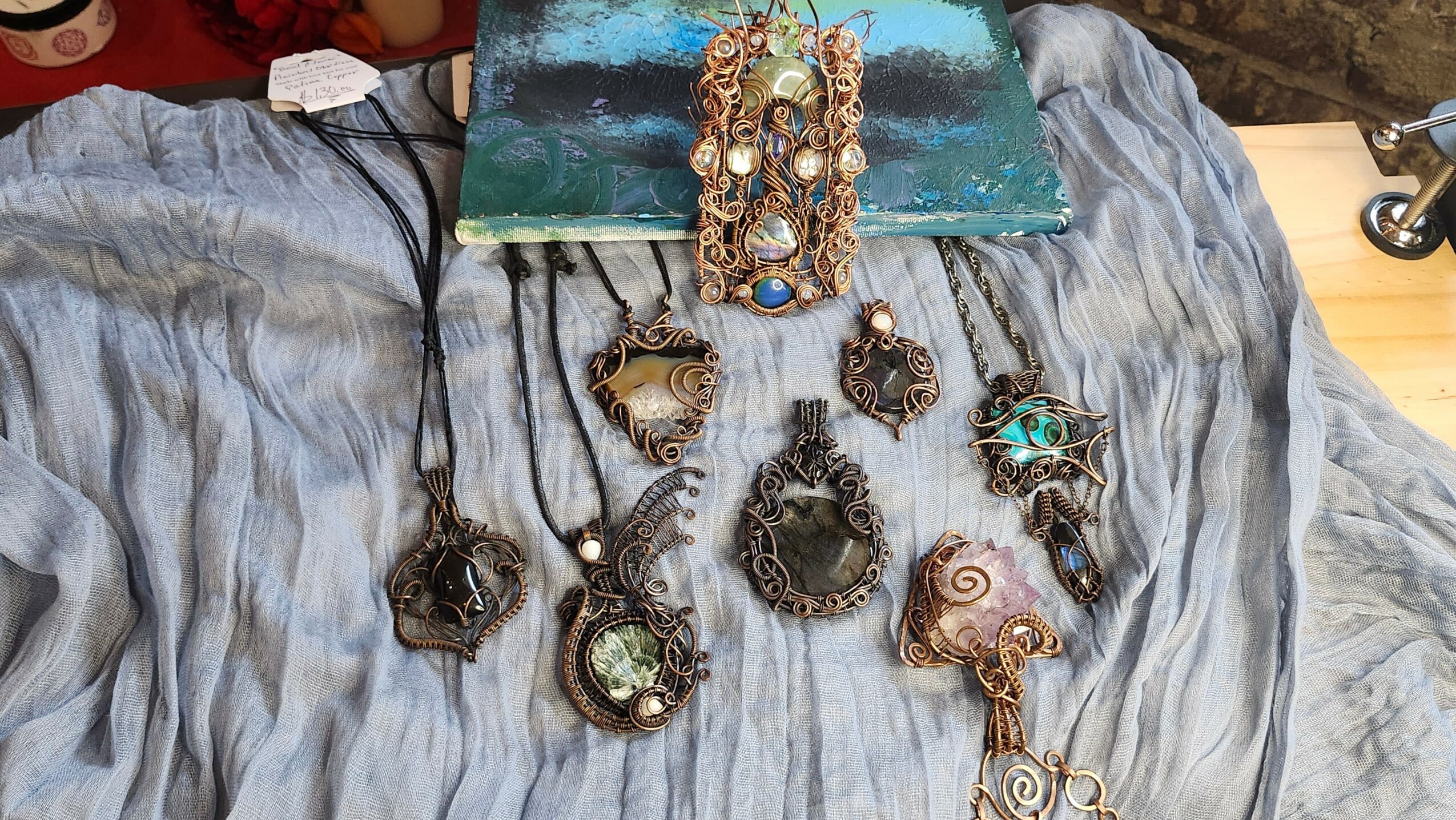 Collection of jewelry including necklaces and pendants displayed on a gray fabric surface.
