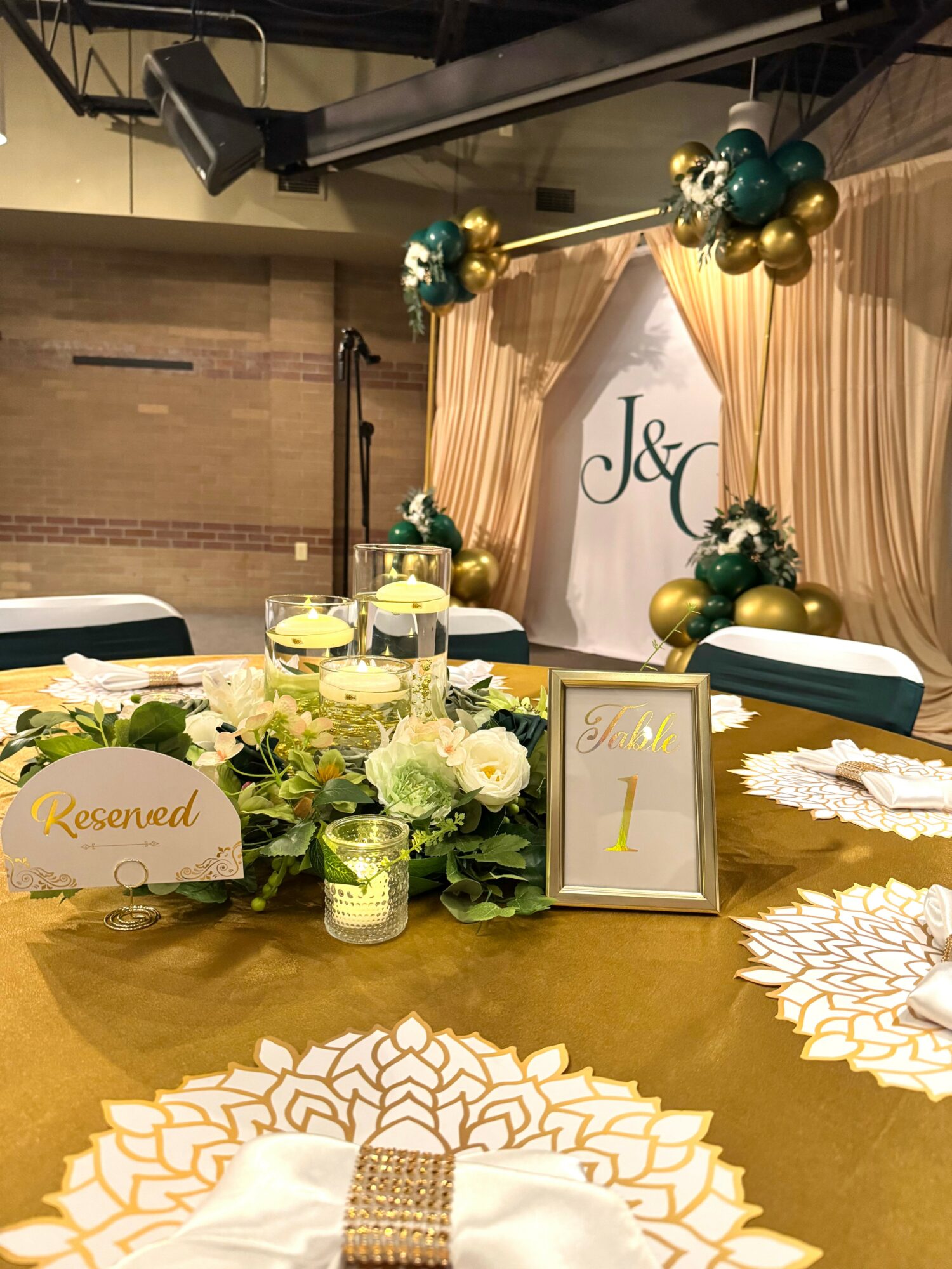 Table decorated with flowers, candles, and a reserved sign, with a backdrop featuring initials and balloon decorations.