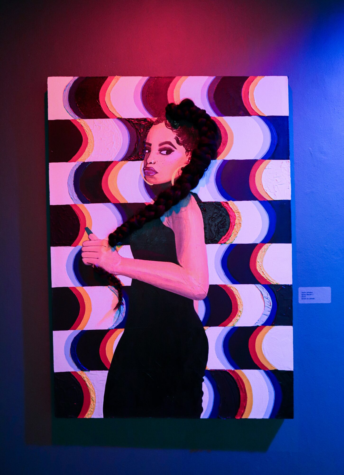 Portrait of a woman with dark hair in a black dress, standing in front of a colorful, wavy patterned background.