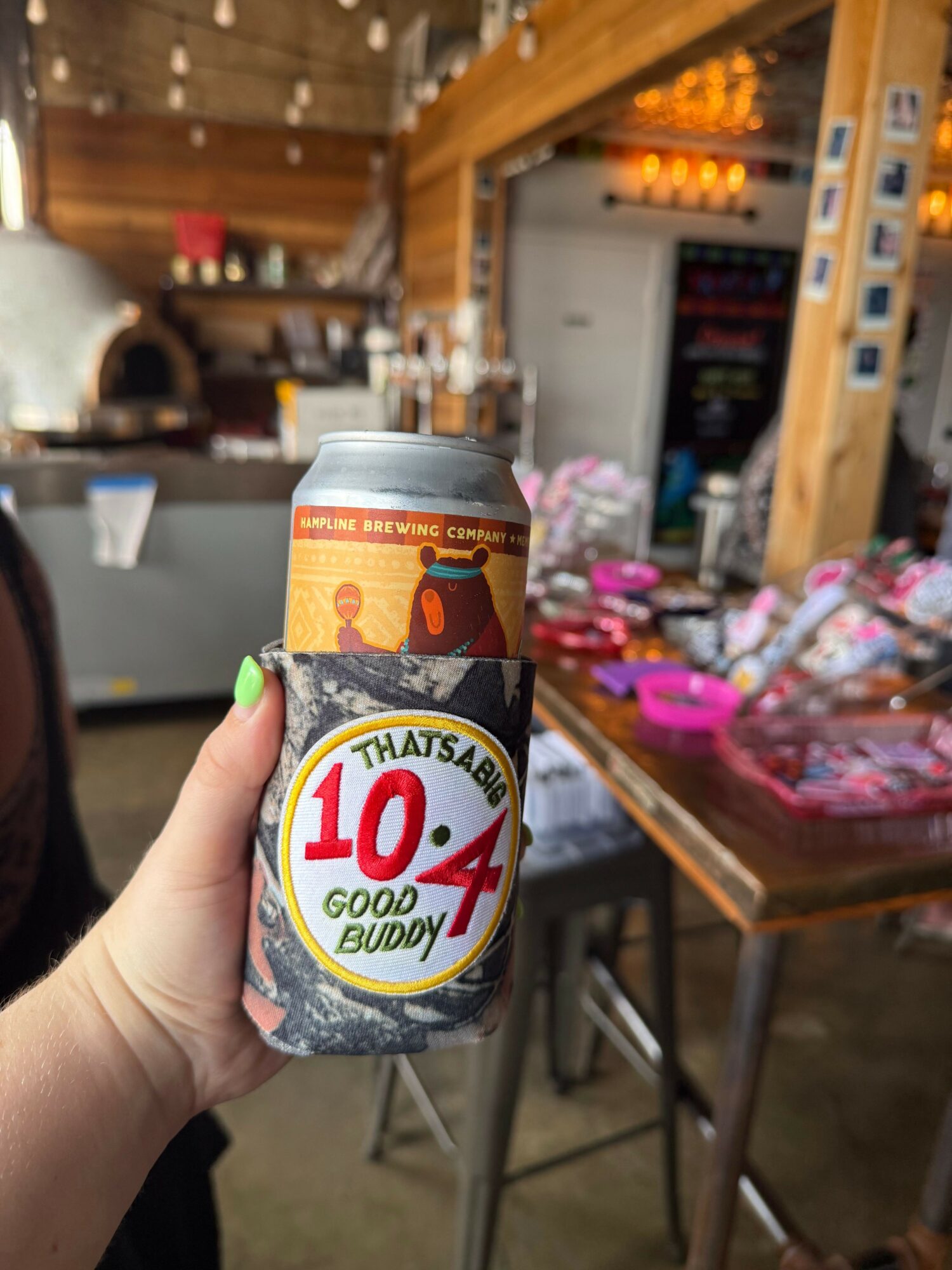 Person holding a can of 100% natural apple juice in a store with shelves of products in the background.