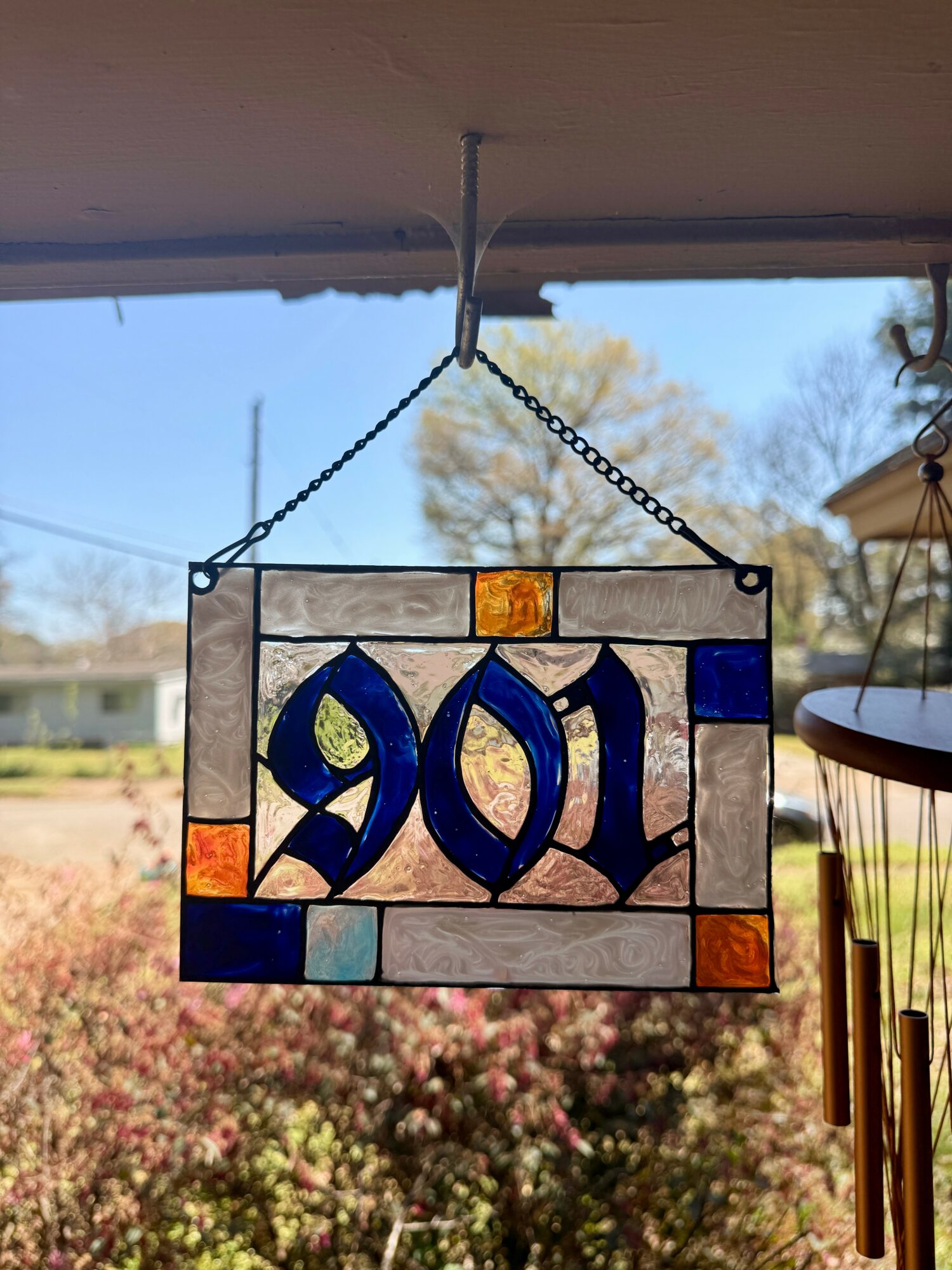 Stained glass hanging decoration with the year 2017, outdoors with trees and sky in background.