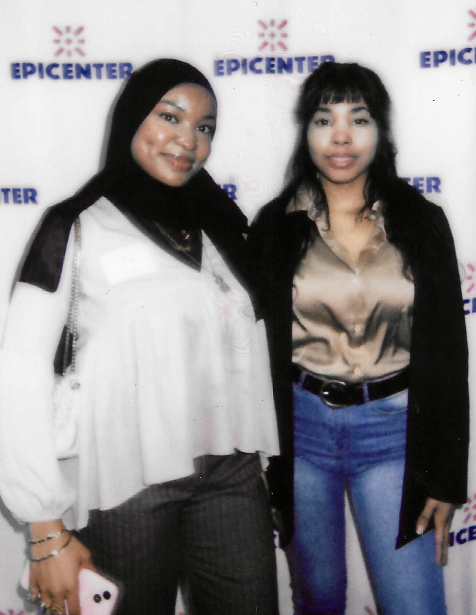 Two women standing together in front of a backdrop with the word EPICENTER repeated, smiling at the camera.