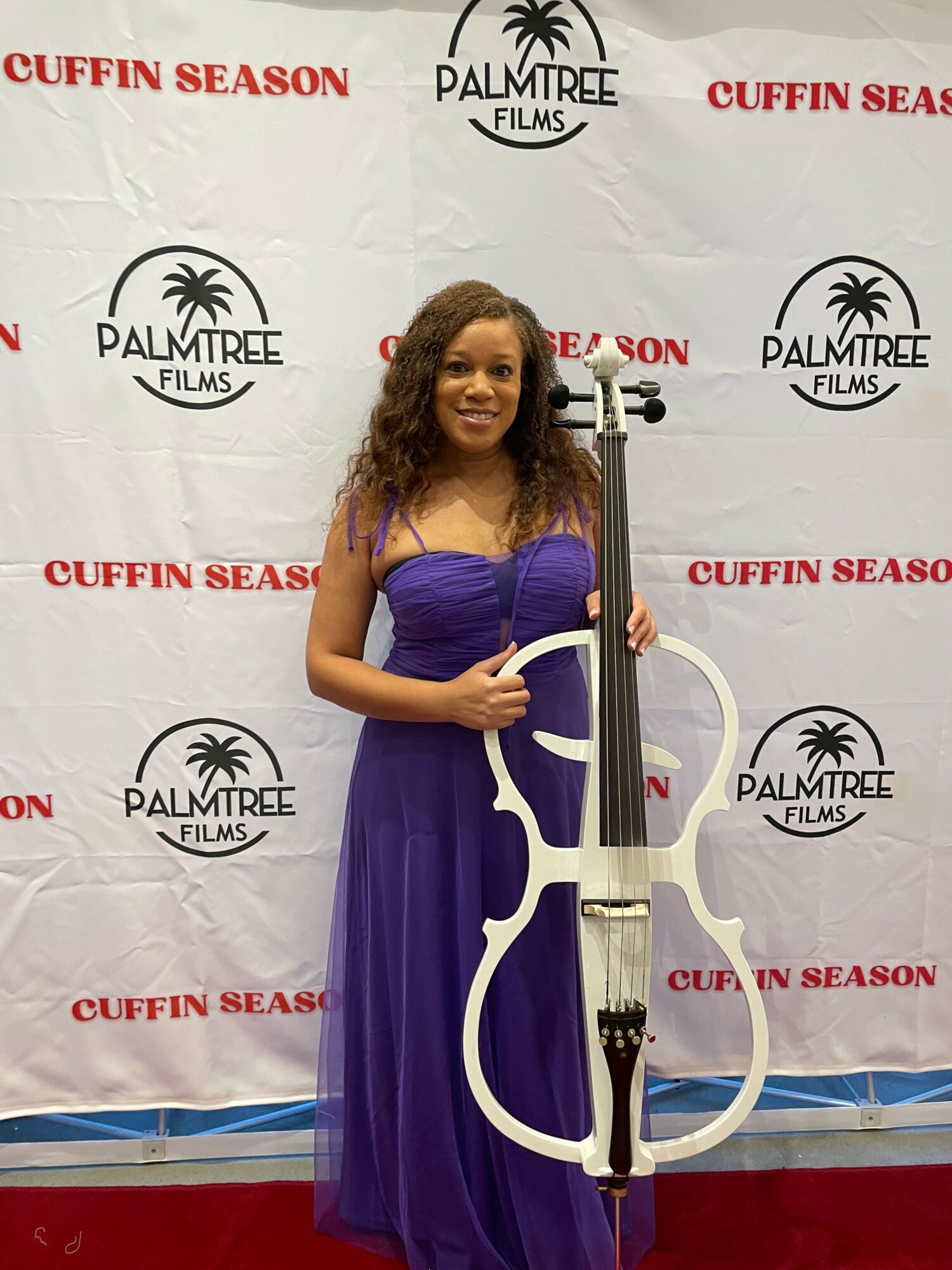 Woman in purple dress holding a sword in front of a Palm Tree Lounge backdrop.