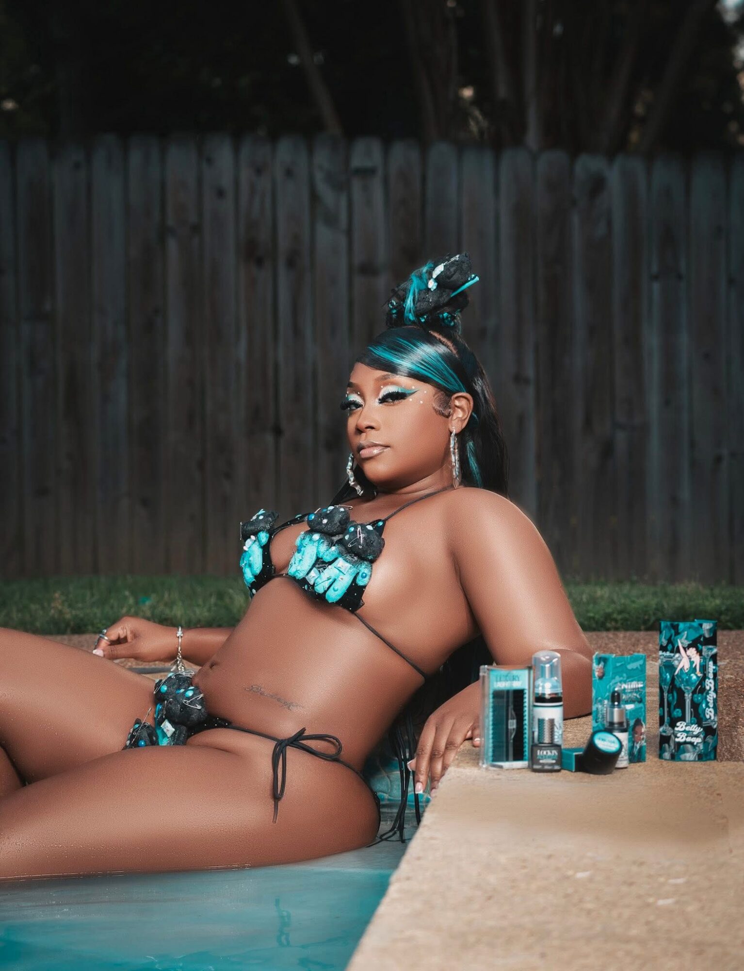 A person in a black swimsuit reclines beside a pool, with several product containers on the edge.