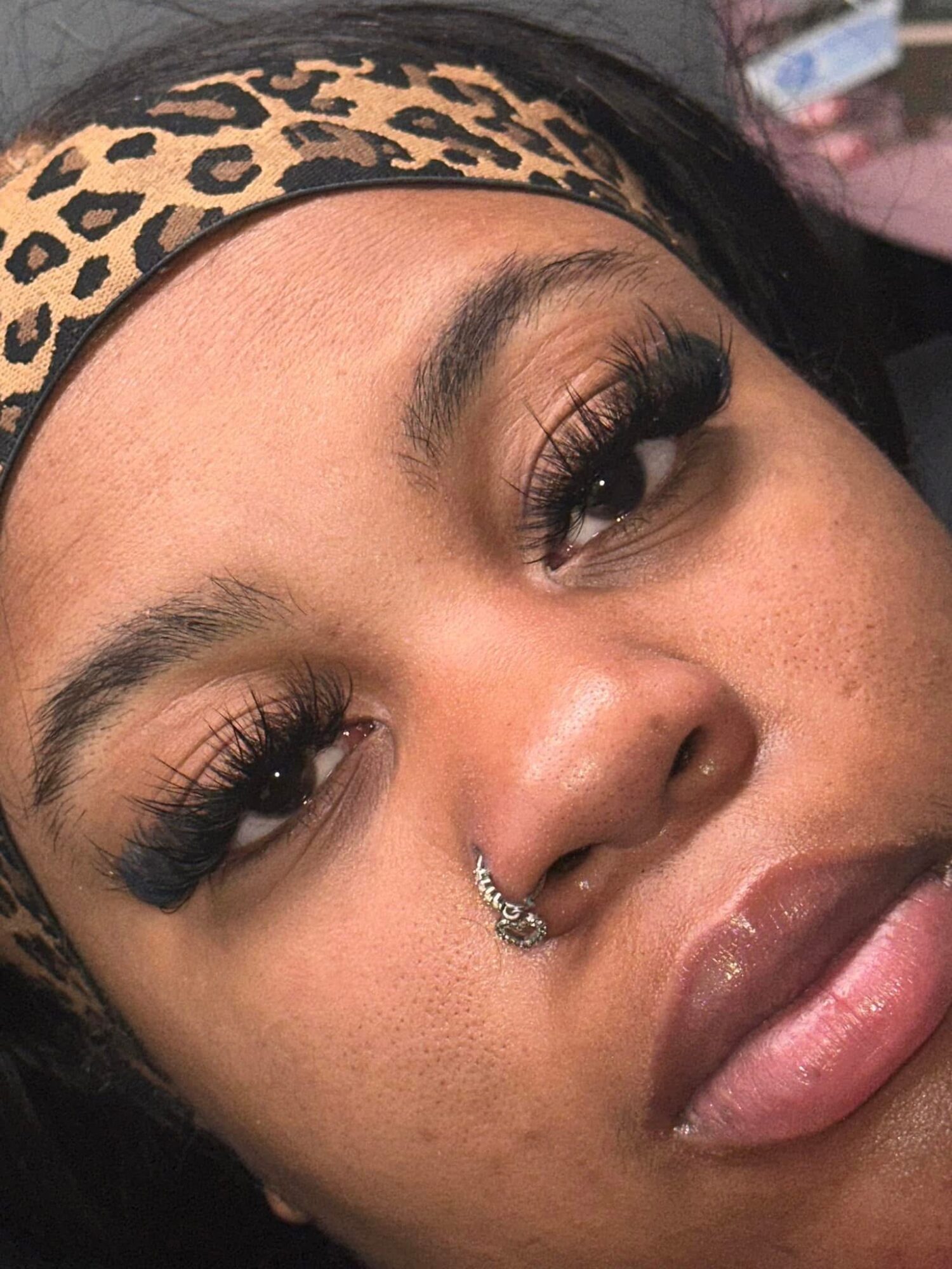 Close-up portrait of a person wearing a leopard-print headband and nose ring.